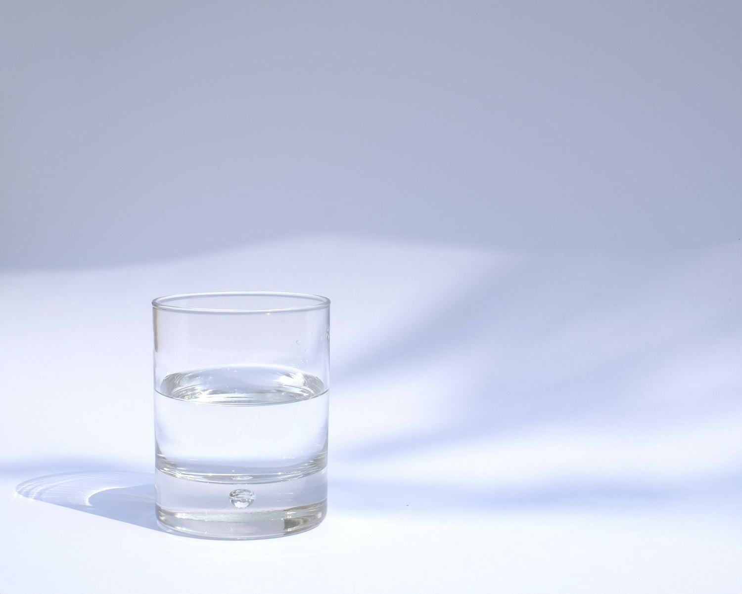Vaso de agua transparente con luz natural, evocando el hábito de beber más agua