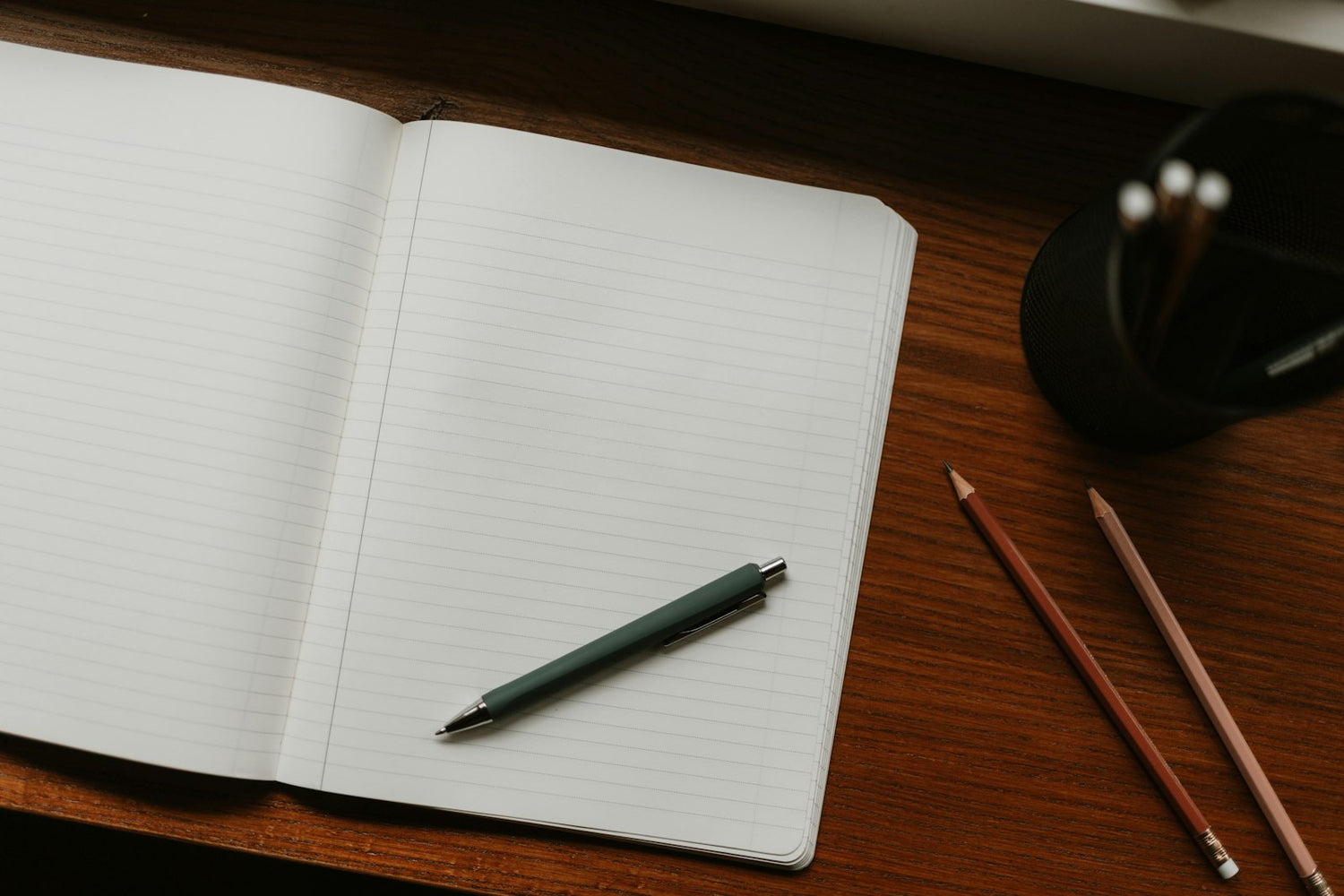 Cuaderno abierto con bolígrafo sobre una mesa de madera, evocando el hábito de escribir un diario